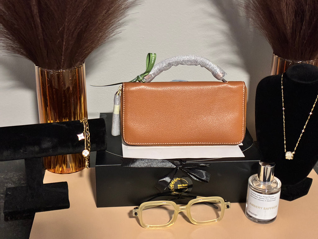 Brown wallet displayed on a mannequin with sunglasses, perfume bottle, and necklace in the background.